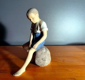 Figur: dreng siddende på en sten.