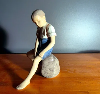 Figur: dreng siddende på en sten.