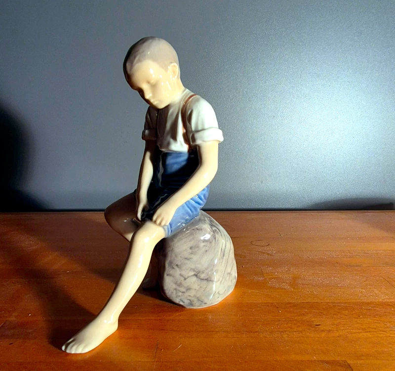 Figur: dreng siddende på en sten.